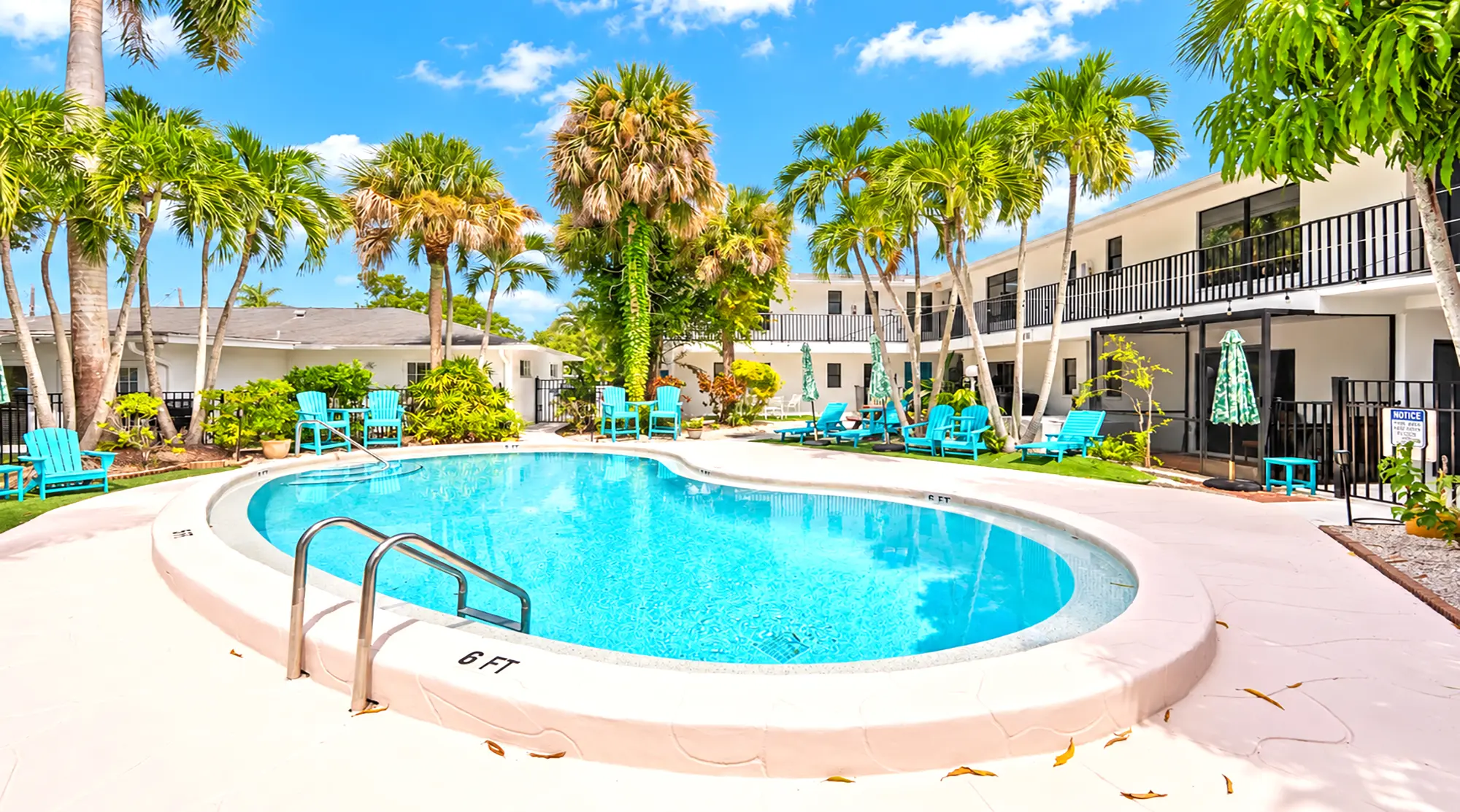 A swimming pool surrounded by a patio with palm trees and rows of bright blue chairs at a resort.